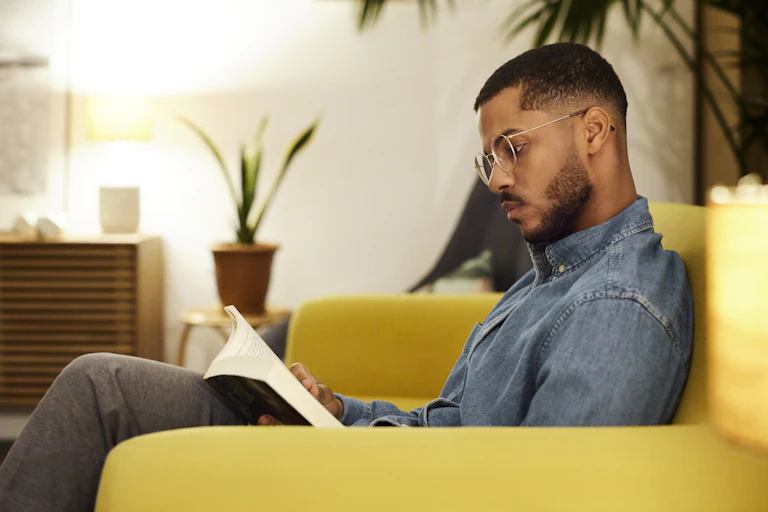 Man on couch reads a book