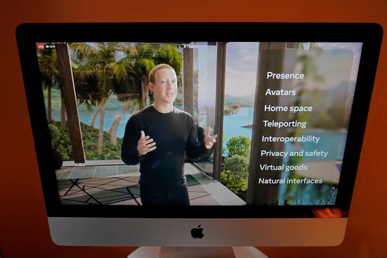 Facebook CEO Mark Zuckerberg speaking in front of a Metaverse VR screen.