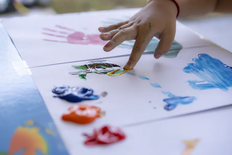 Close-up of child's hand fingerpainting on sheets of paper