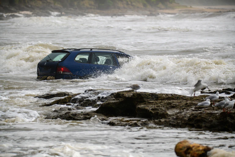 Waves crash into a vehicle swept out to sea after flash flooding near the Wye River, Victoria, Friday, January 16, 2026.
