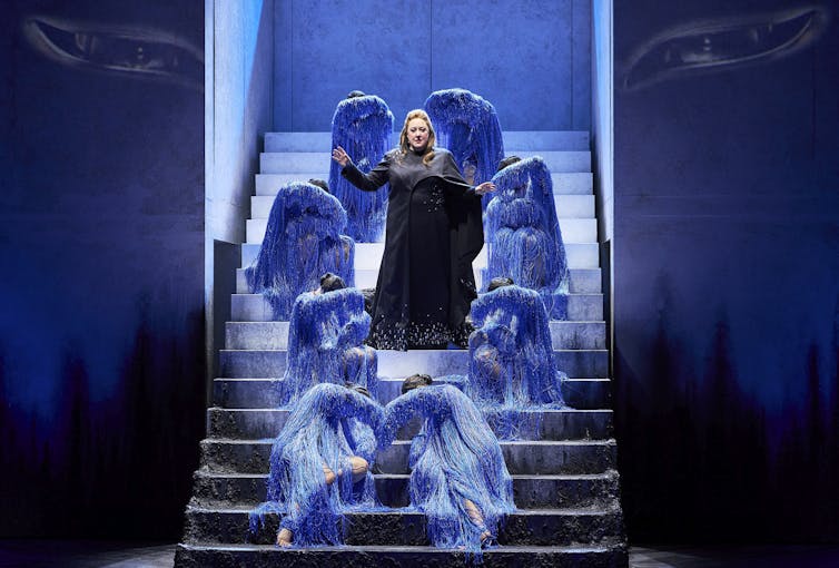 Turandot stands on stairs, surrounded by dancers in blue.