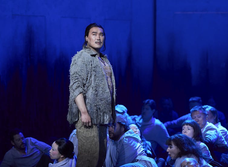 Kim stands on a blue stage.