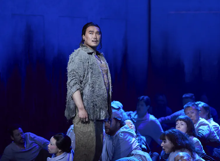 Kim stands on a blue stage.