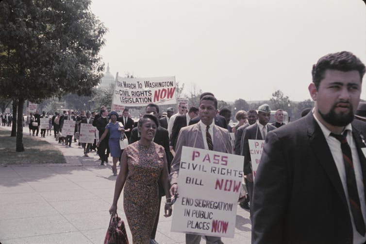 A large group of people marching with signs urging passage of a civil rights bill.