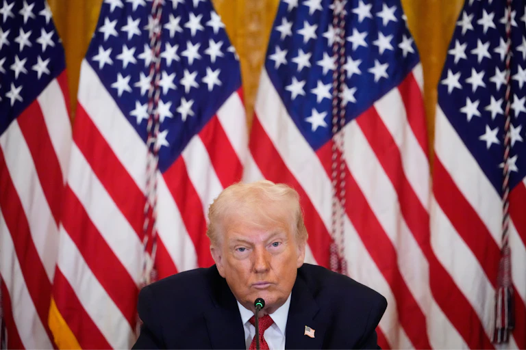 President Trump sits before a row of American flags.