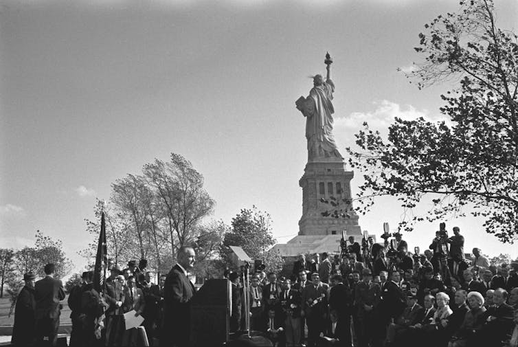 A crowd of people gathered at the base of the Statue of Liberty.