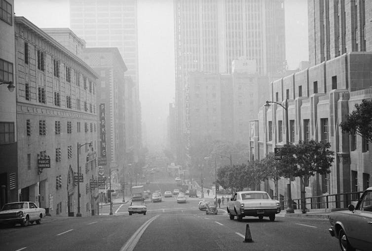 A smoggy view of a street with 1950s-vintage cars in downtown LA.