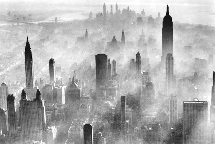 An aerial view of New York City, with only the tops of buildings clearly visible through the smog.
