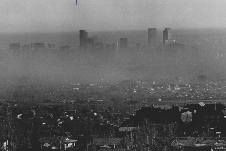 Only the tops of the buildings are visible through the layer of smog in this view of the skyline from a distance.