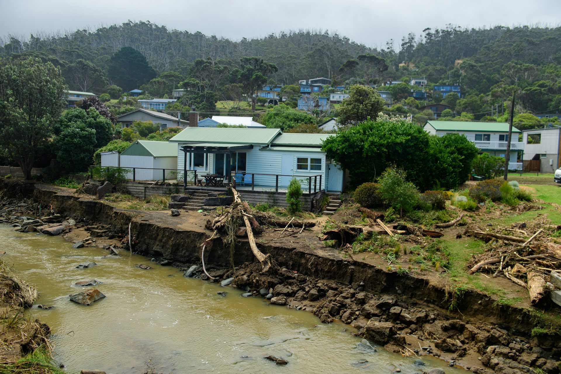 A house sits very close to a gouged out Separation Creek, after flash flooding near the Wye River, Victoria, Friday, January 16, 2026