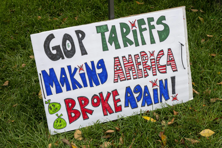 A placard with 'GOP Tariffs Making America Broke Again' written on it.