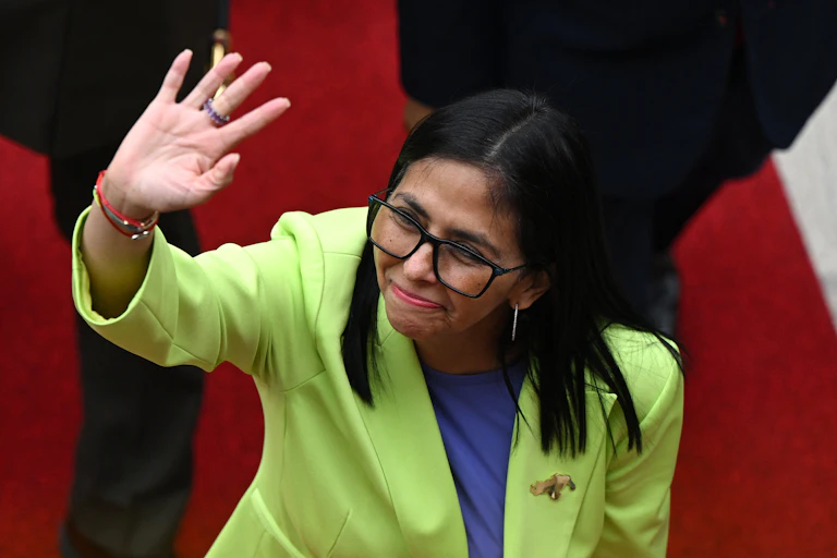 A woman in a lime jacket waves.
