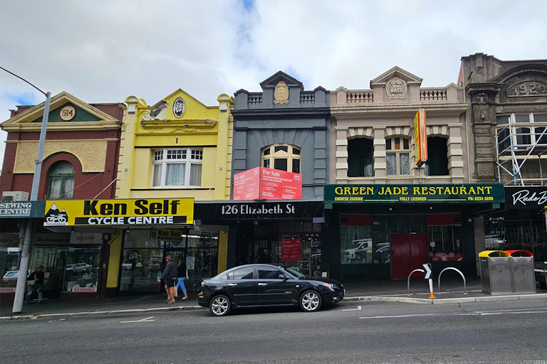 A row of six two storey shopfronts on Elizabeth St, each one a slightly different design and colour.