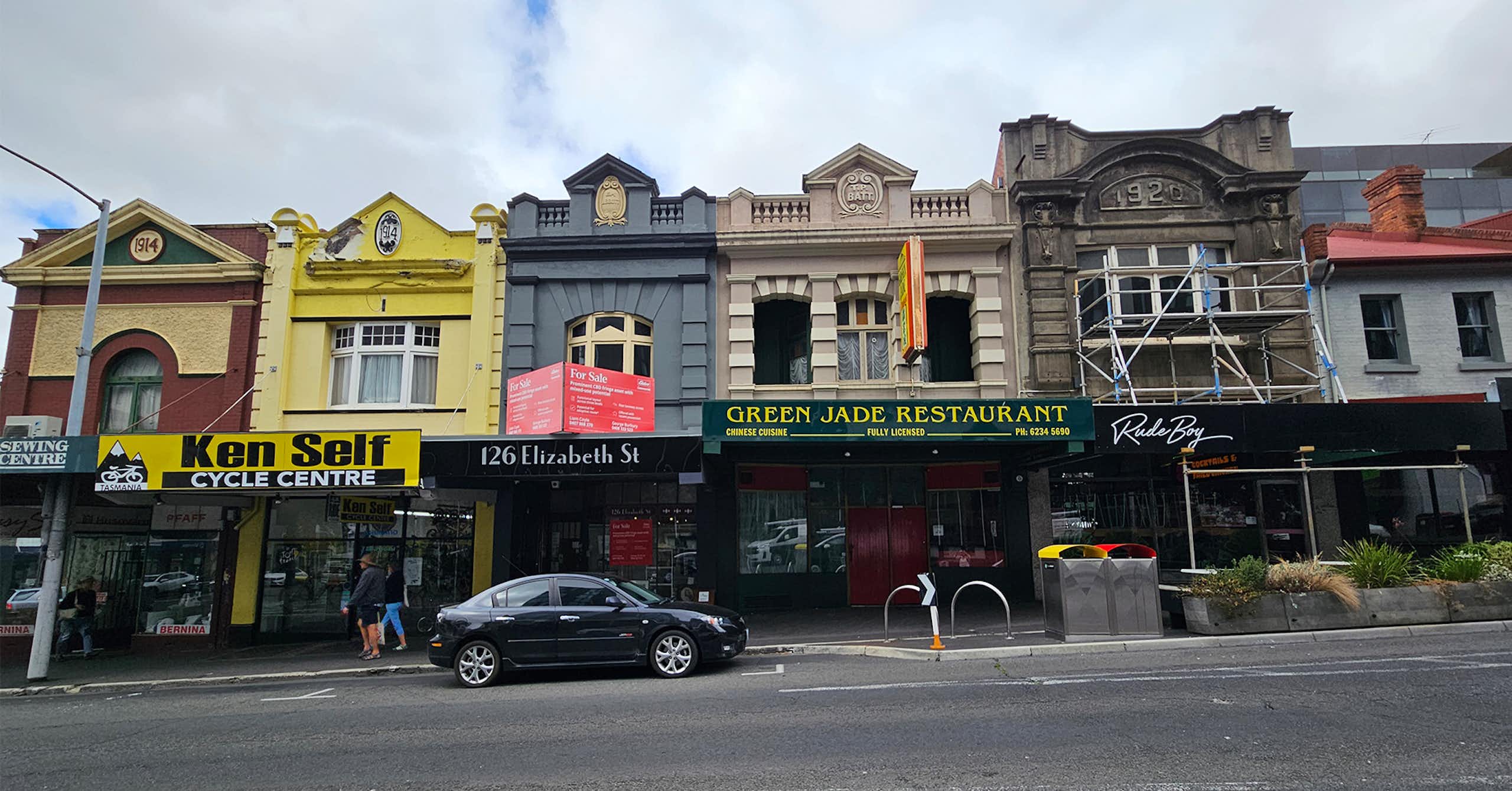 A row of six two storey shopfronts on Elizabeth St, each one a slightly different design and colour.