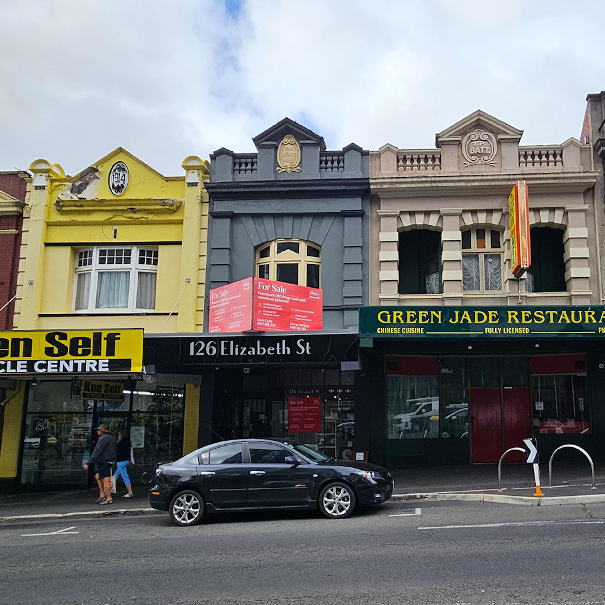 A row of six two storey shopfronts on Elizabeth St, each one a slightly different design and colour.