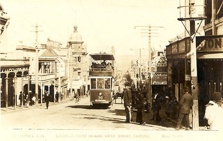 A sepia photo of a busy streetscape, with a trolley bus running through the middle.