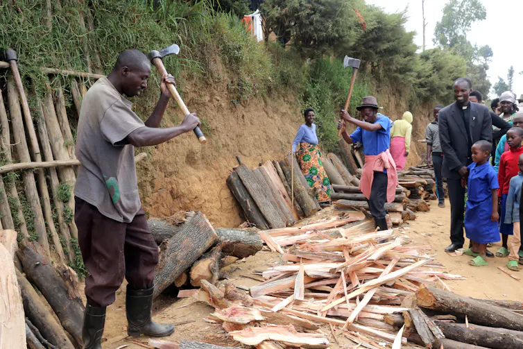 Man chops firewood while others look on