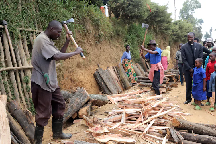Man chops firewood while others look on