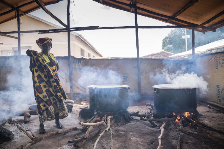 Woman beside large cooking pots