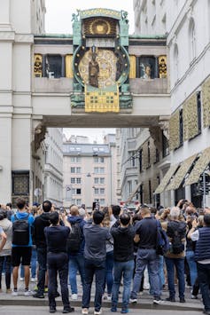 Reloj y mucha gente con teléfonos móviles levantados y mirándolo.