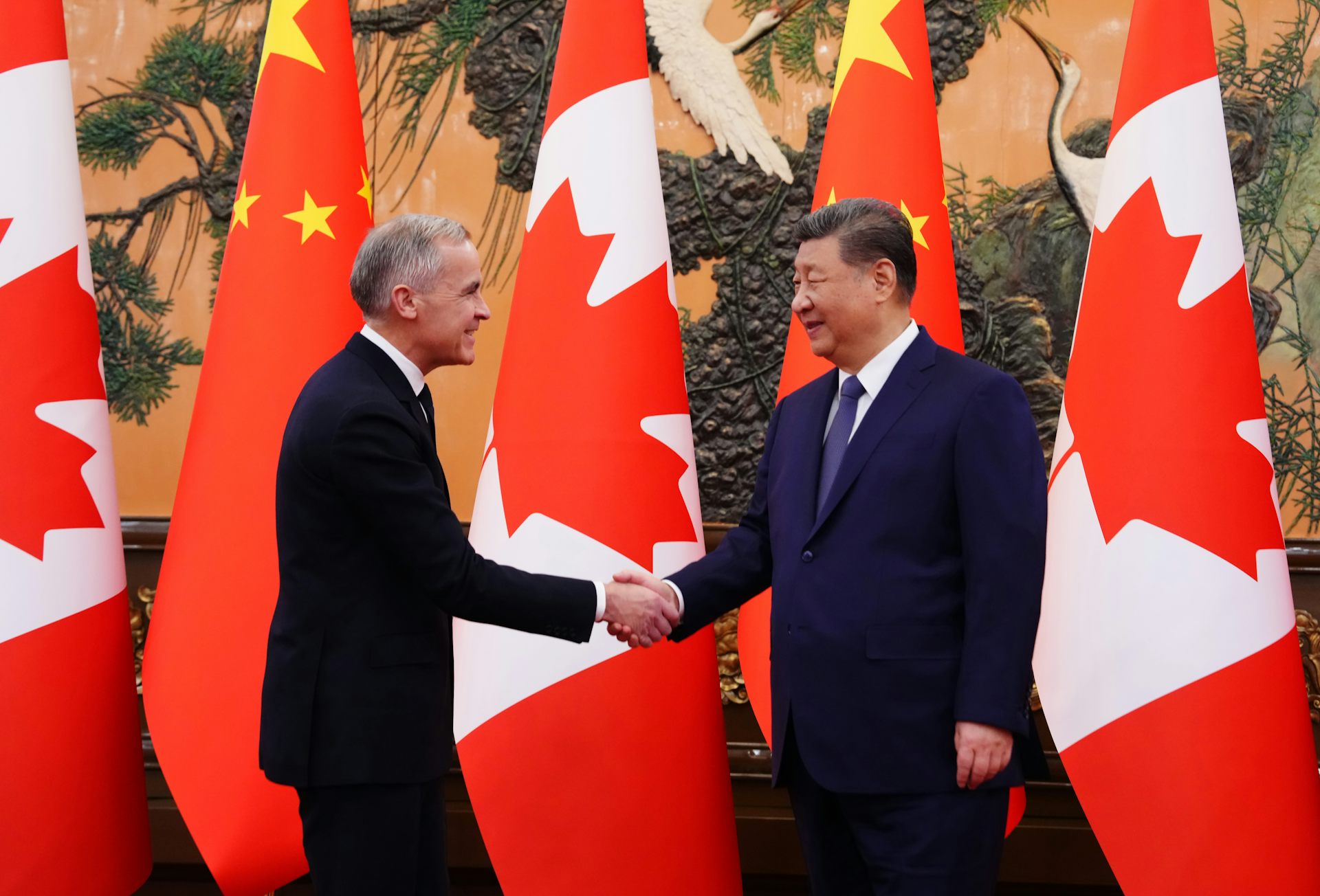 A middle-aged white man shakes hands with a middle-aged Chinese man
