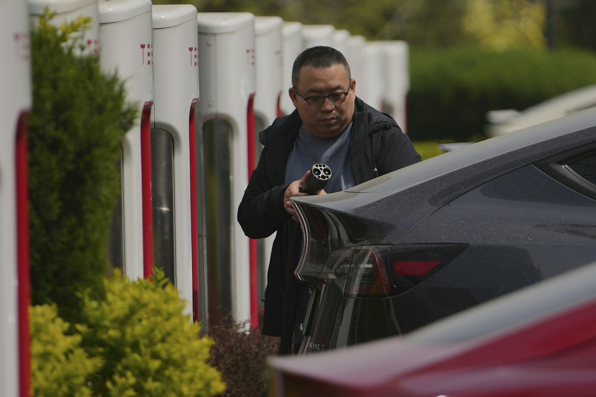A man charges his electric vehicle
