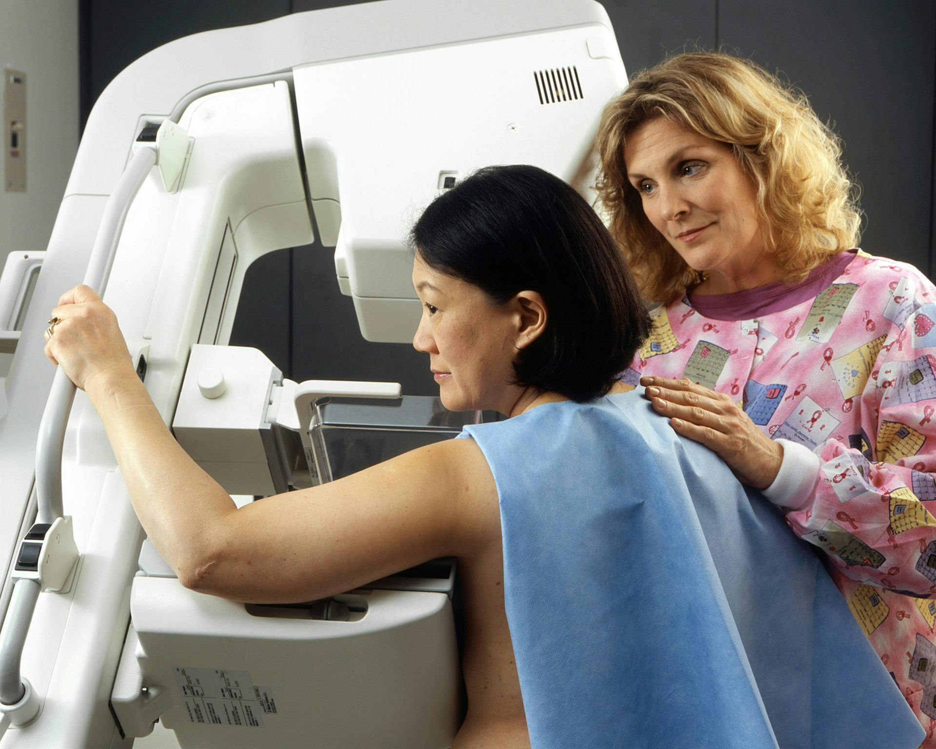 A health worker assisting a woman getting a mammogram