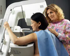 A health worker assisting a woman getting a mammogram