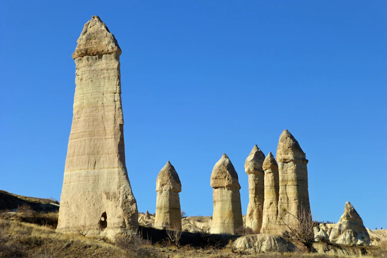 A series of phallic rock formations against a blue sky.