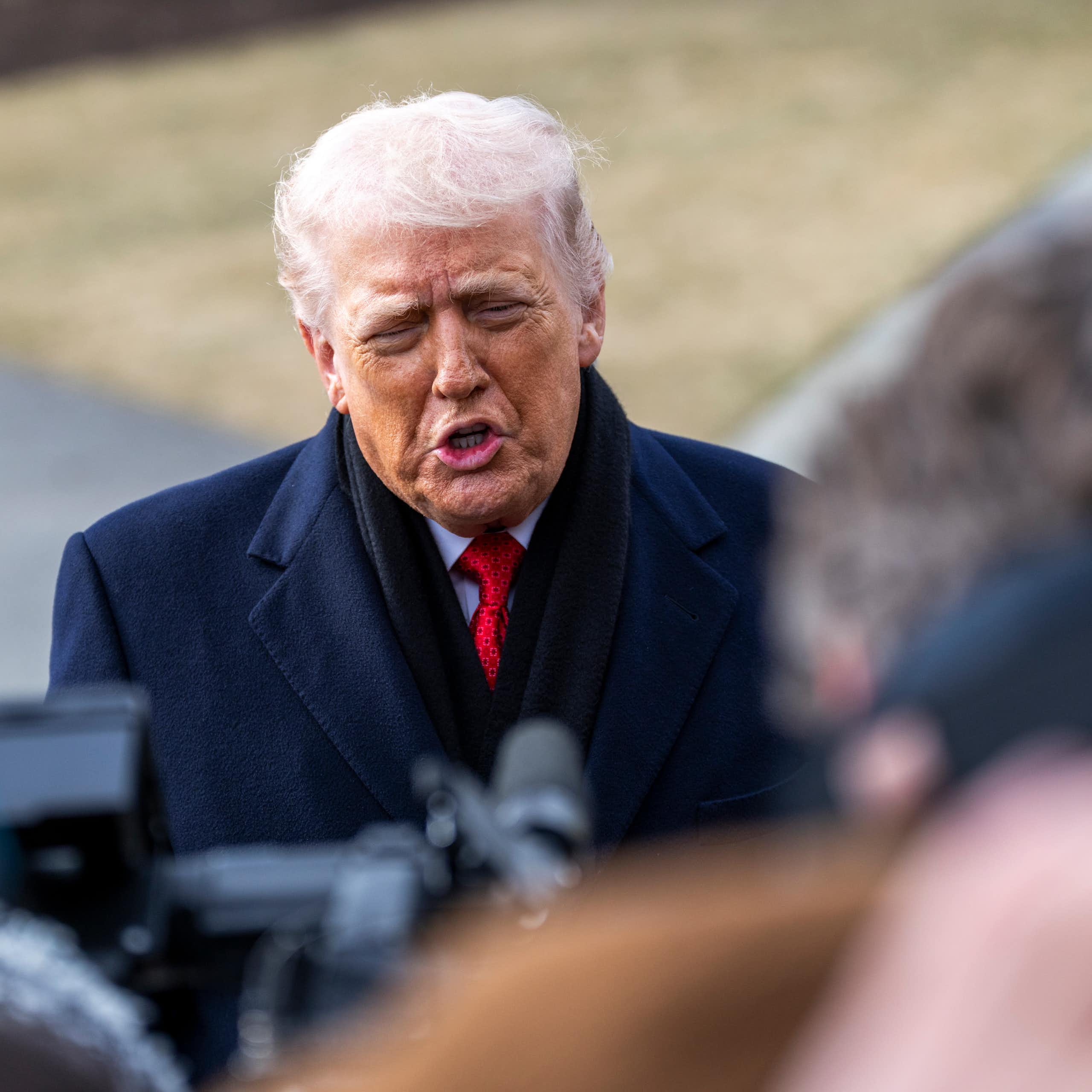 Donald Trump responds to questions from reporters on the White House lawn.