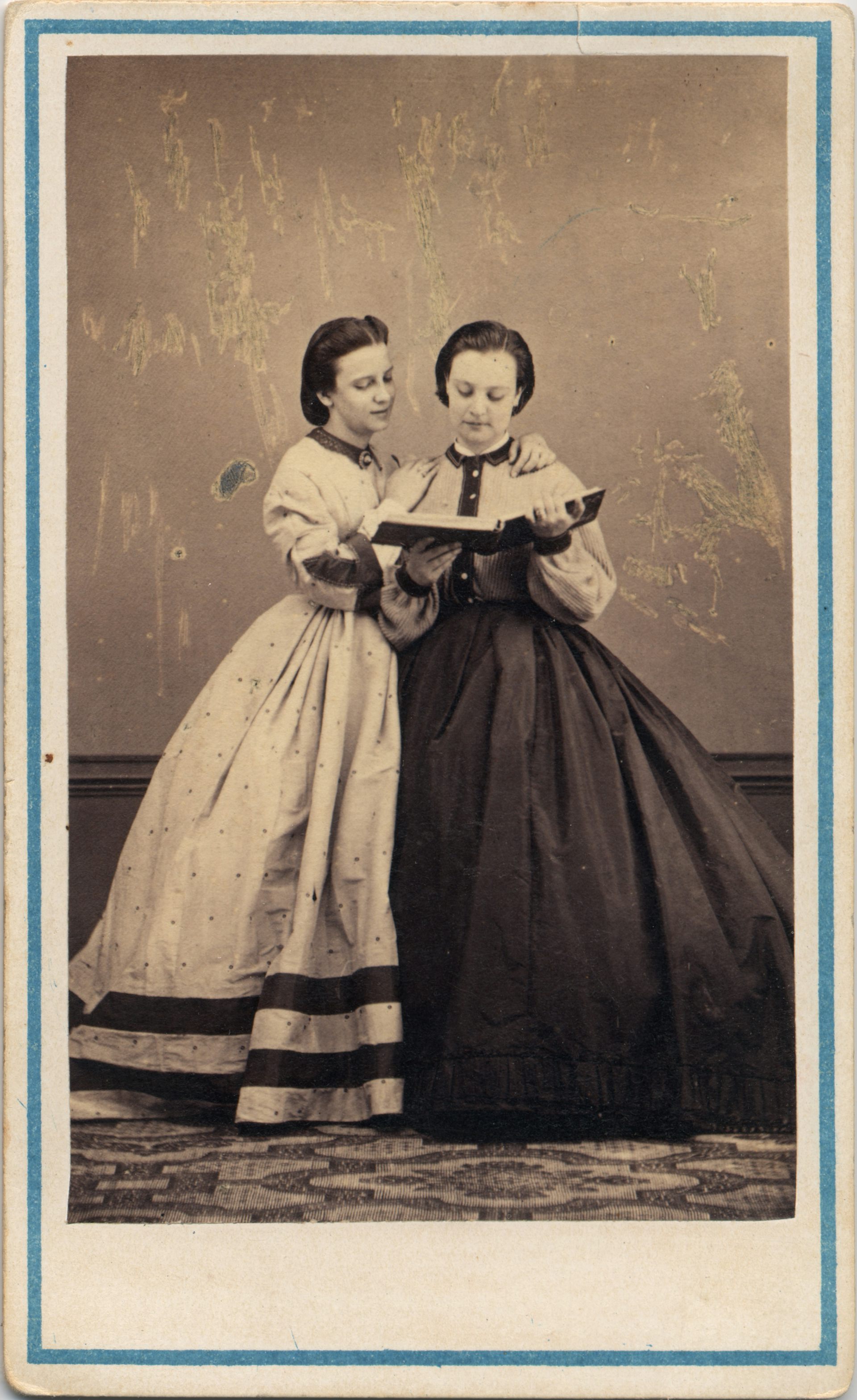 Two women from the 19th century are reading a book.