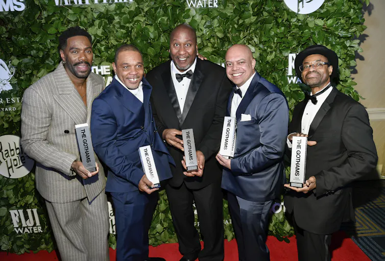 Five men stand in a row holding awards.
