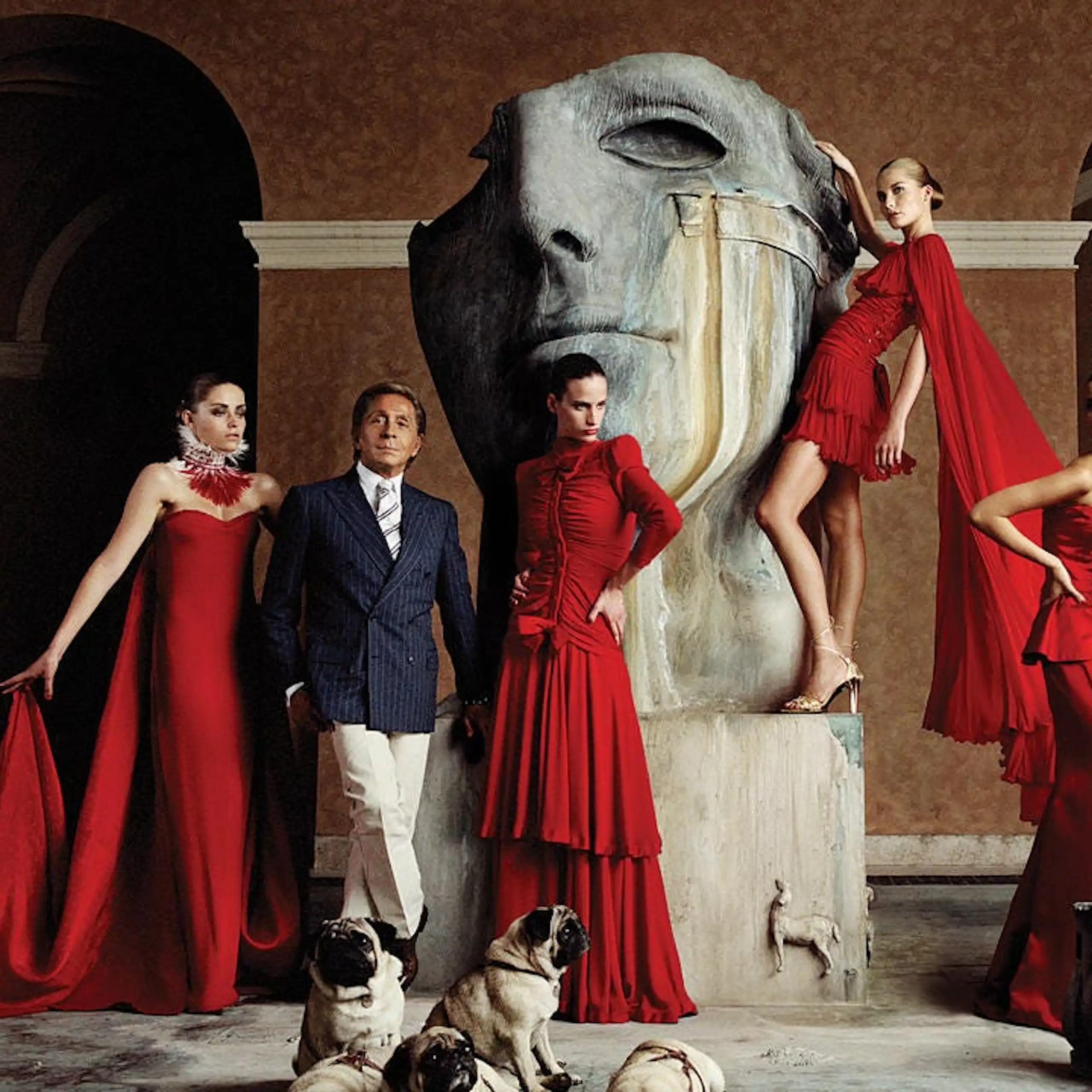 Un hombre de traje rodeado de mujeres con vestidos rojos.