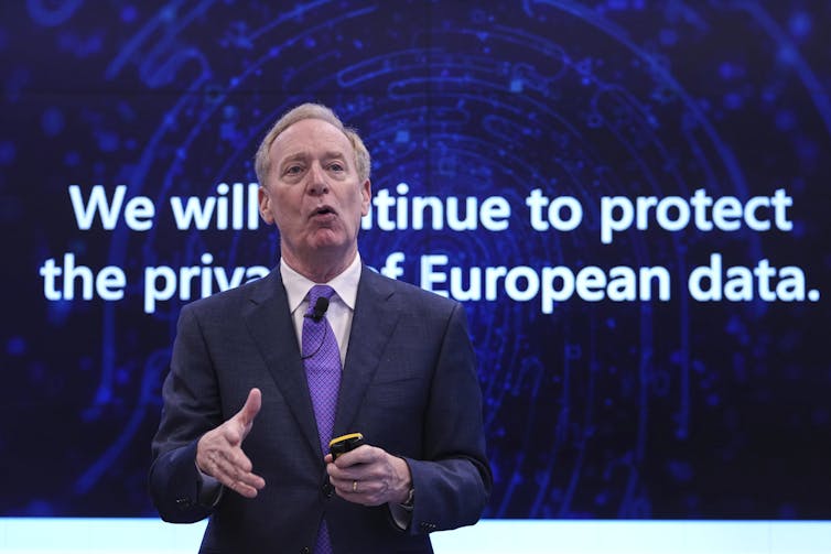 A man stands in front of a sign that reads We Will Continue to Protect European Data.