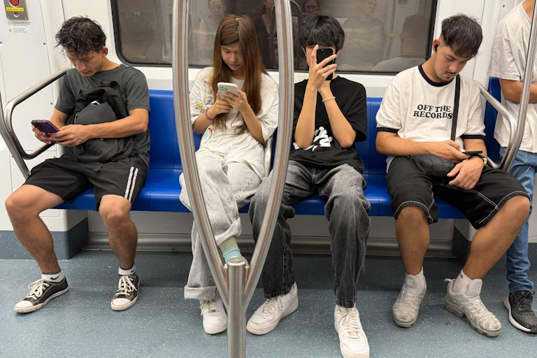 Pasajeros en el metro centrados en sus teléfonos móviles.