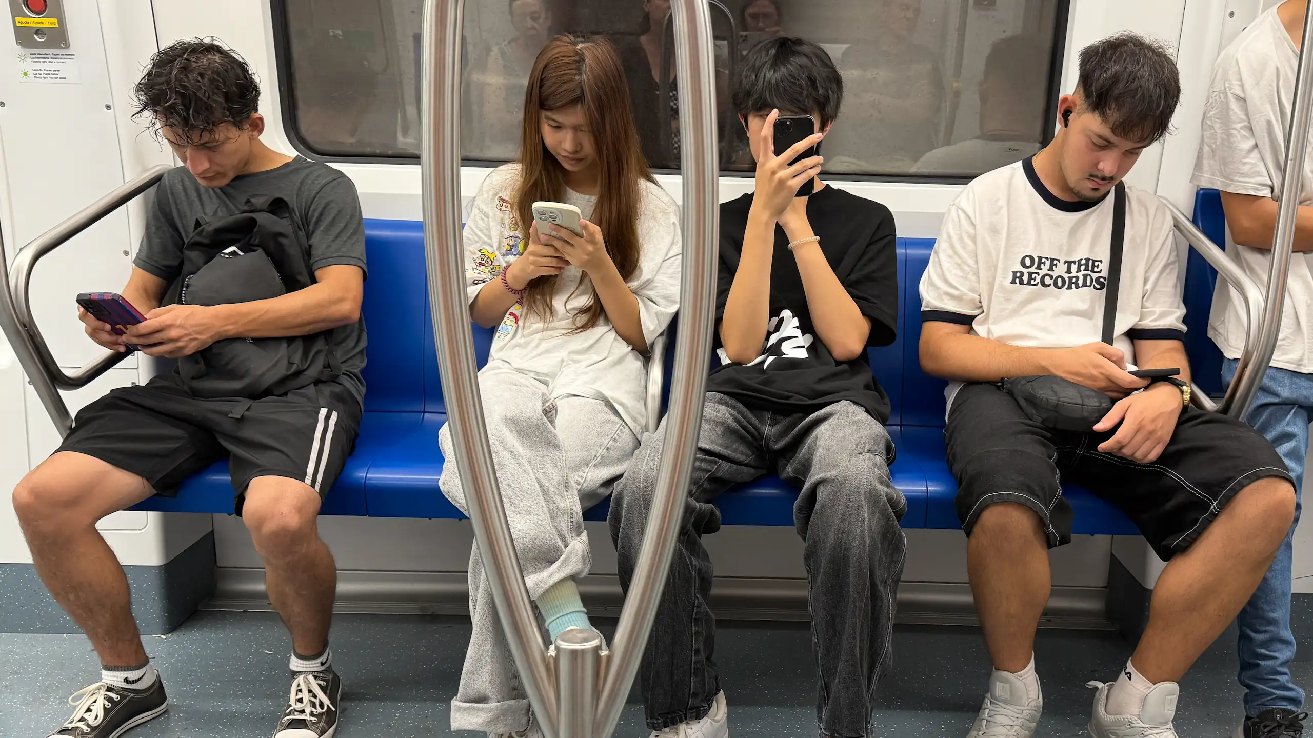 Pasajeros en el metro centrados en sus teléfonos móviles.