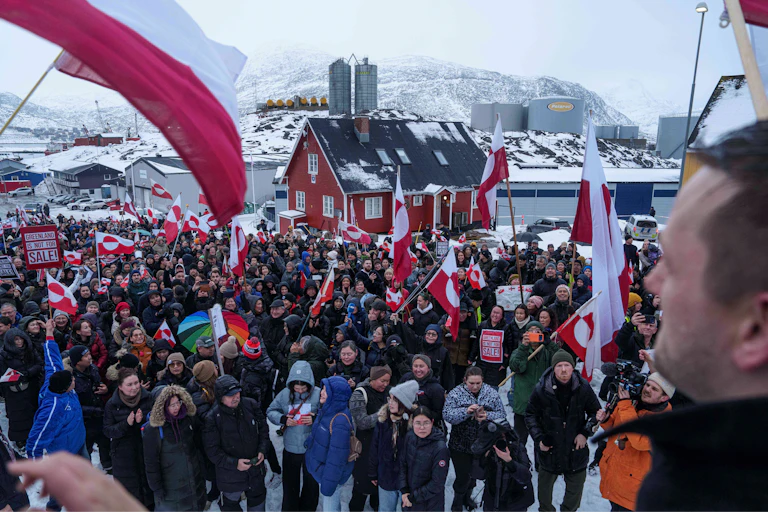A crowd waves red and white flags in a snowy landscape.