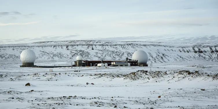 A military base is seen in front of a snowy hillside.