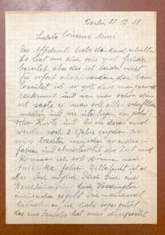 A faded, handwritten letter in blank ink, positioned against a brown surface.