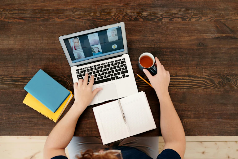 Close up of a virtual meeting on a laptop, notebooks, pen