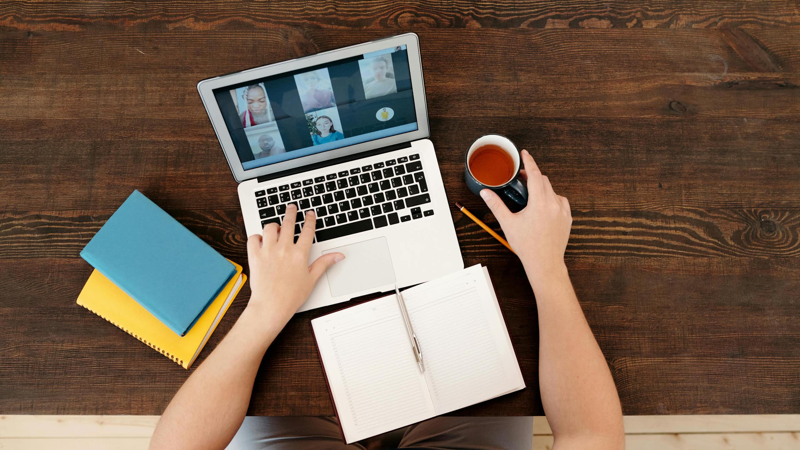 Close up of a virtual meeting on a laptop, notebooks, pen