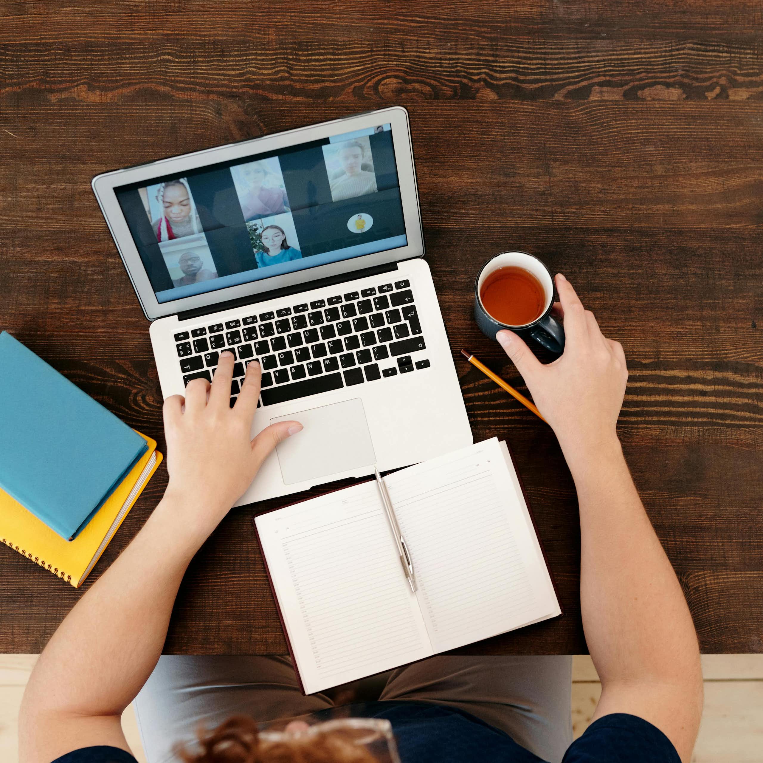 Close up of a virtual meeting on a laptop, notebooks, pen