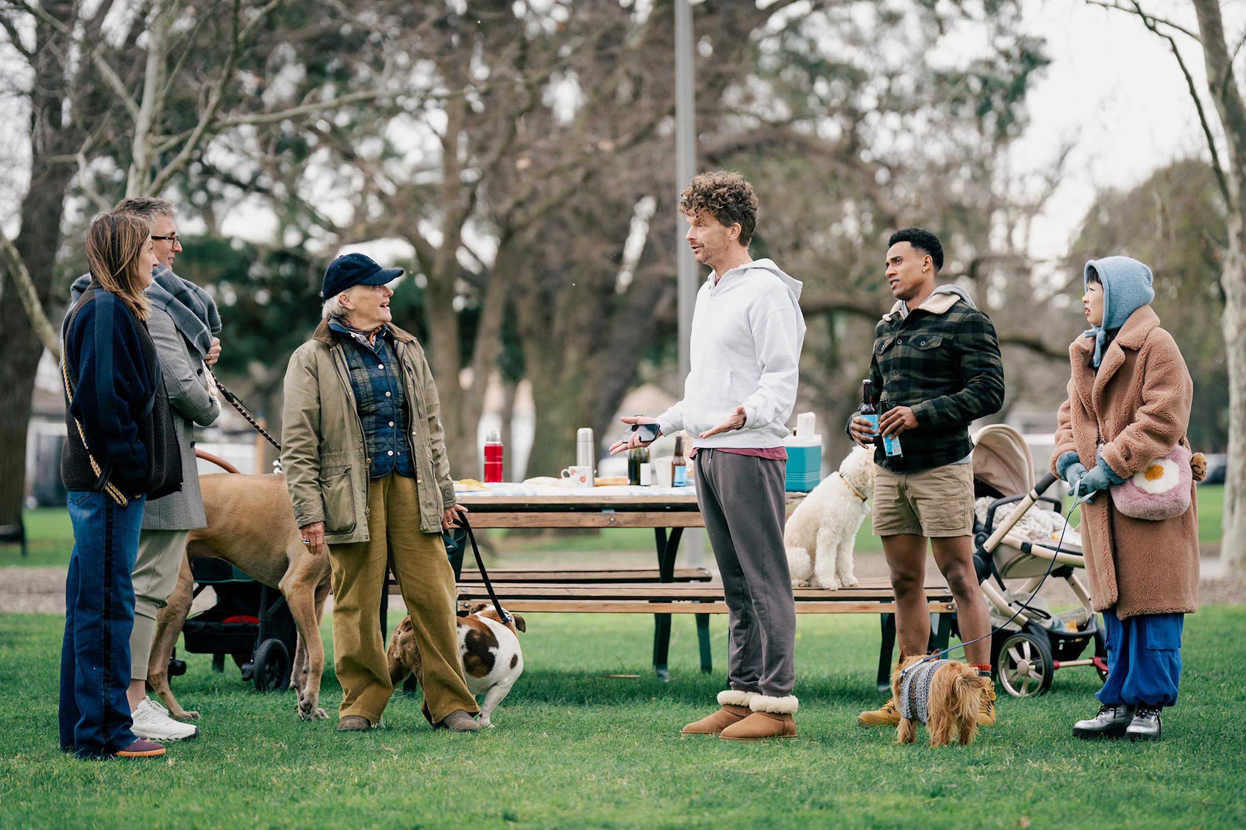 Production image: a group of people in a park, with their dogs.