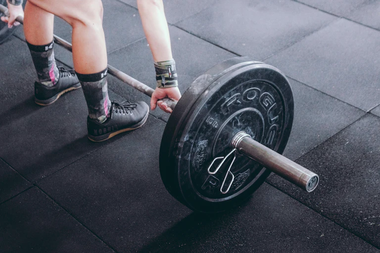 Woman crouches down to lift a weight in a gym.