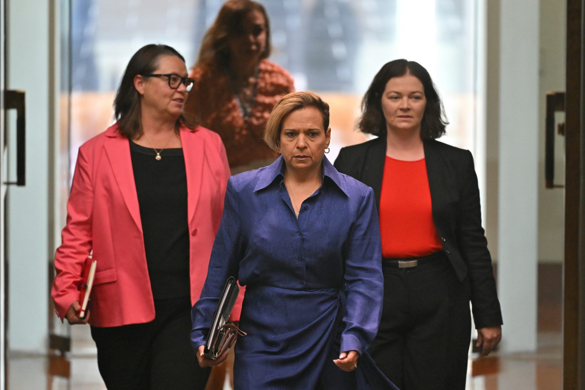 Three women walk into the Australian parliament, led by the attorney-general.