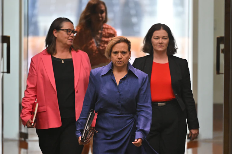 Three women walk into the Australian parliament, led by the attorney-general.
