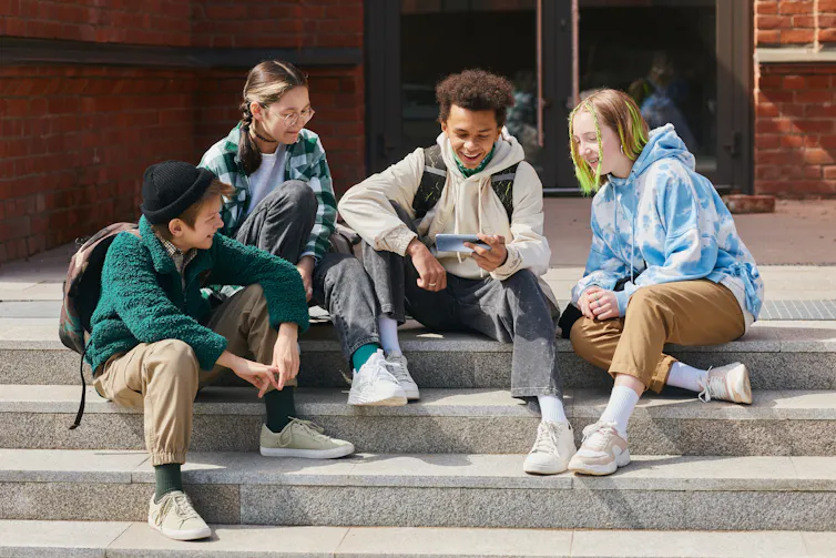 Teenagers with phone sat on steps