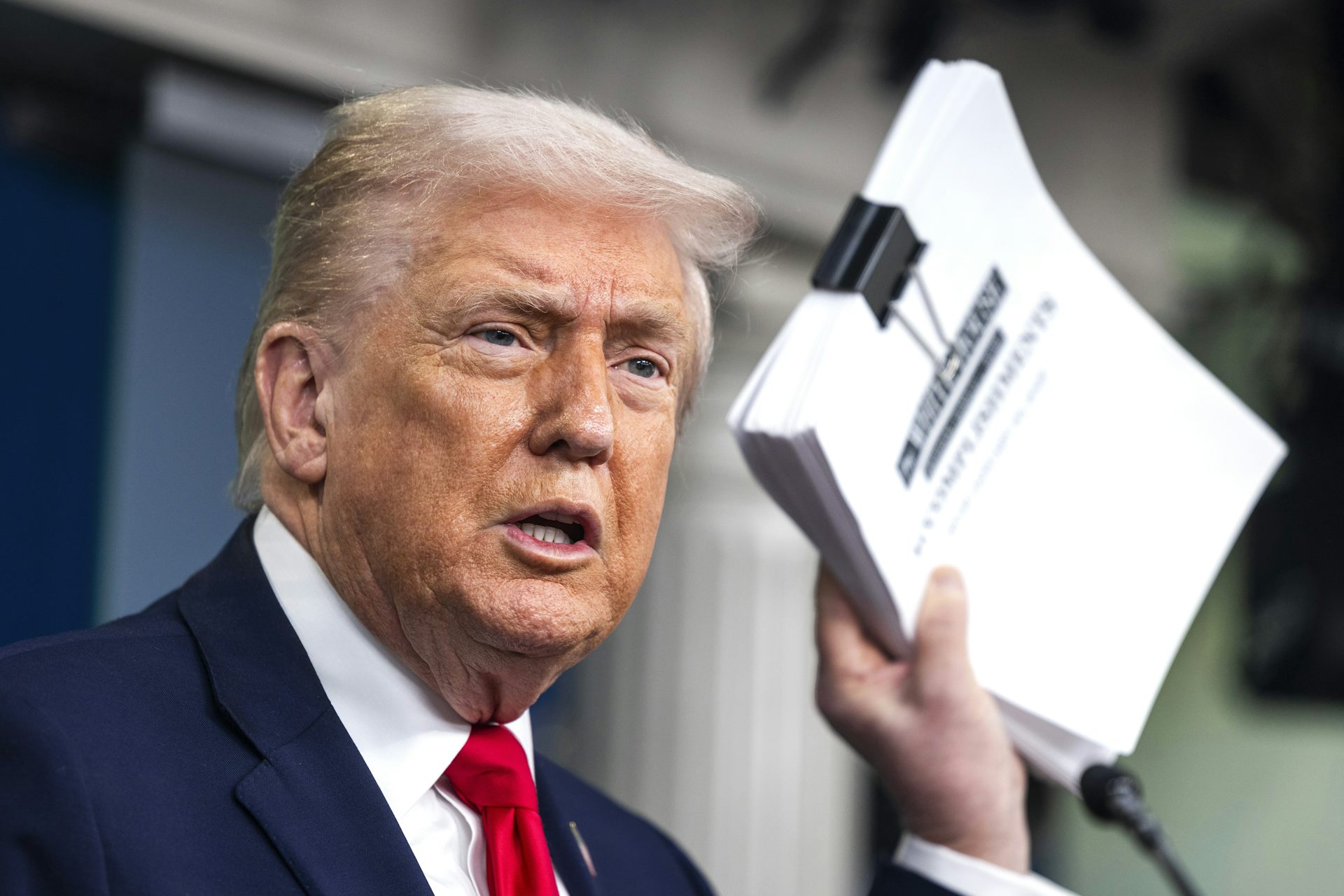 Donald Trump holds a document detailing his administration's accomplishments over the past year.