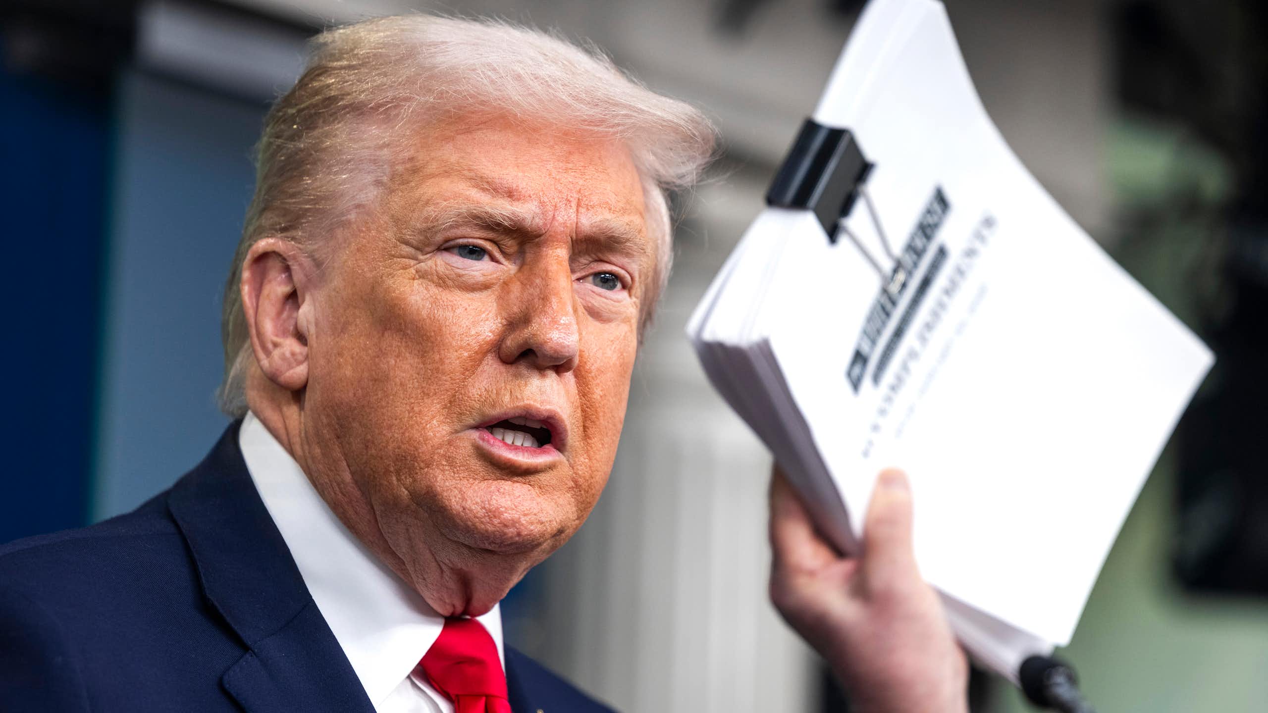 Donald Trump holds a document detailing his administration's accomplishments over the past year.