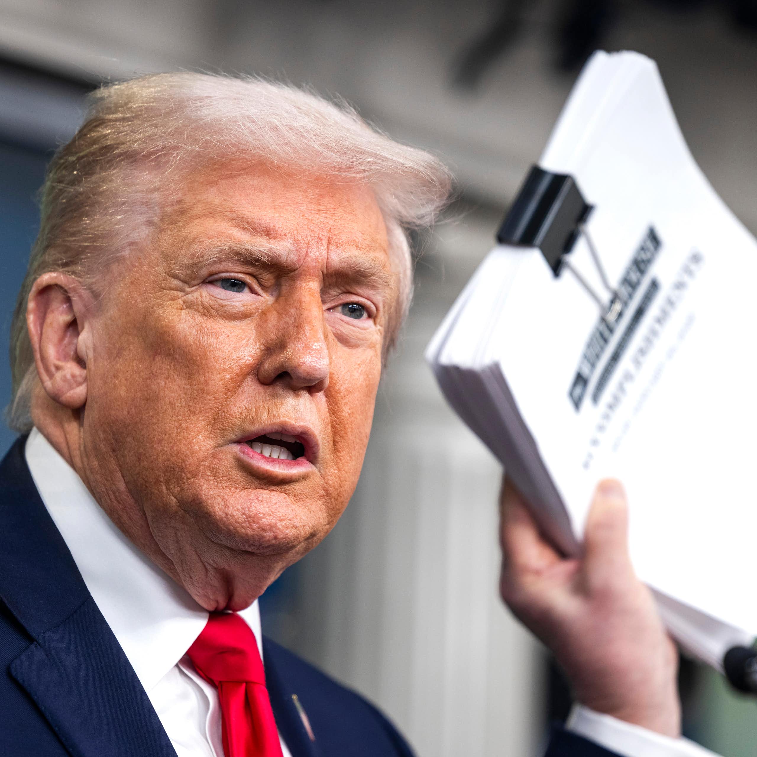 Donald Trump holds a document detailing his administration's accomplishments over the past year.